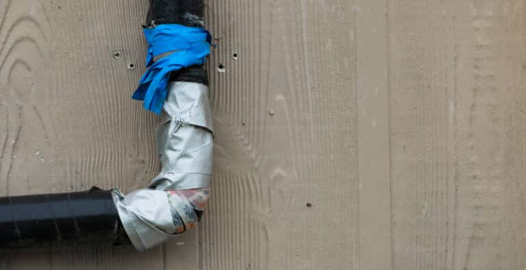 Very bad plumbing job done on a pipe on the outside of a house closeup