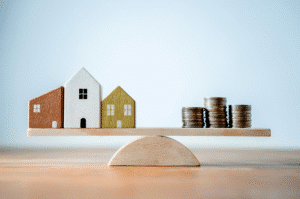 Wooden houses and coins balancing